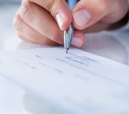a person holding a pen over a piece of paper.