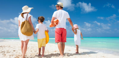 a man and two children are walking on the beach.
