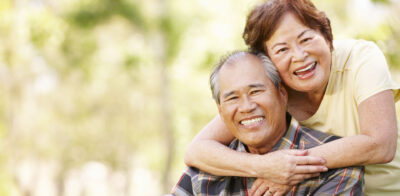 a man and woman hugging each other in a park.