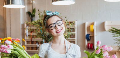 a woman holding a bunch of flowers in a flower shop.