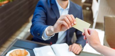 a man handing a business card to a woman.