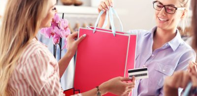 a woman holding a shopping bag and a credit card.
