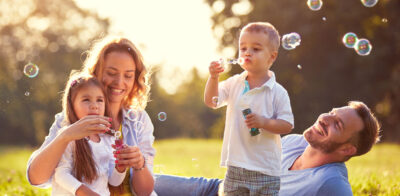 a family blowing bubbles in a field at sunset.